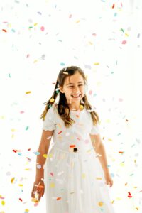 girl closes her eyes as confetti falls on her head