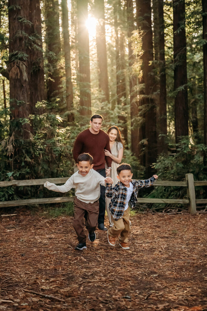 2 boys run towards the camera away from their parents who are watching them laughing