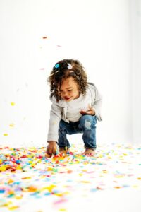 boy picks up confetti off the ground of photography studio