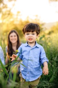 boys holds mustard flower looking at camera