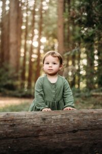 toddler leans against a fallen redwood tree