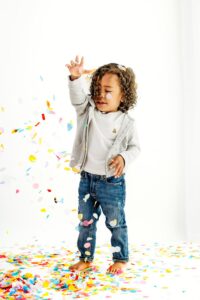toddler watches as confetti falls from his hands