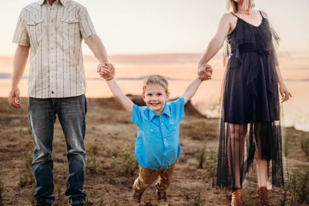 Young boy laughing between his parents during a playful beach moment.