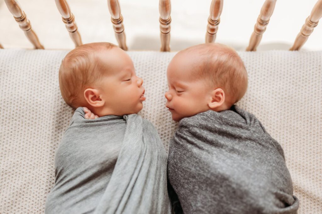 newborn twins sleeping side by side in a vintage crib