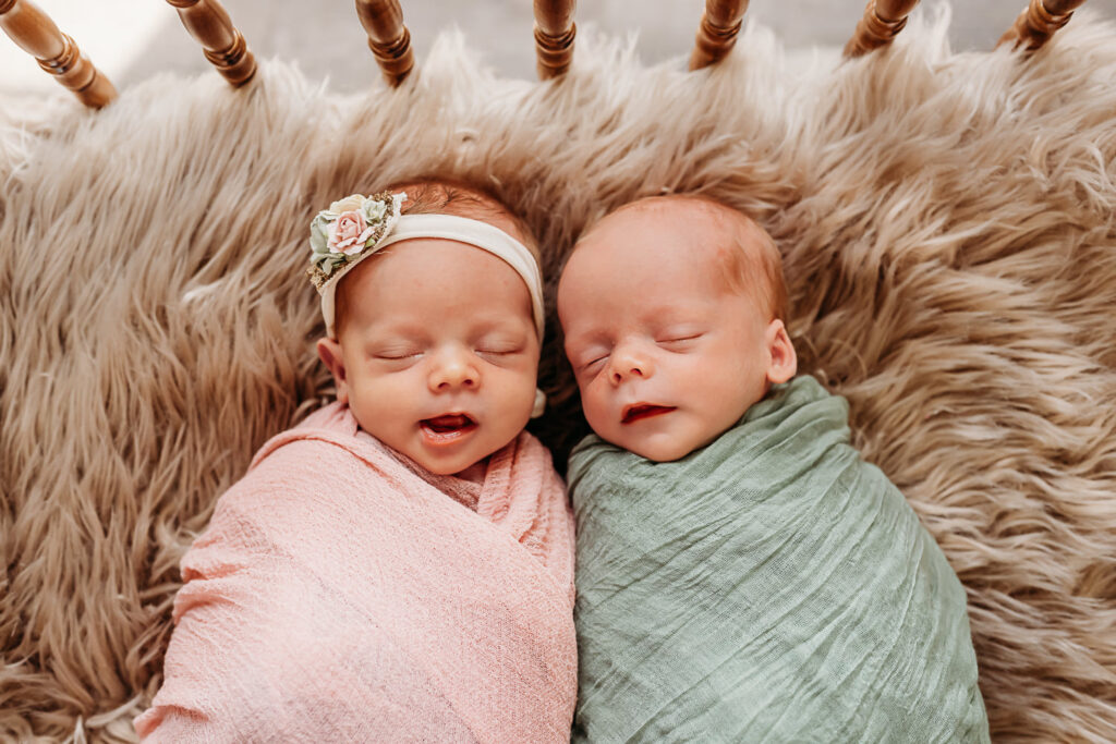 newborn twins sleeping during their photo session. one in pink and one in green