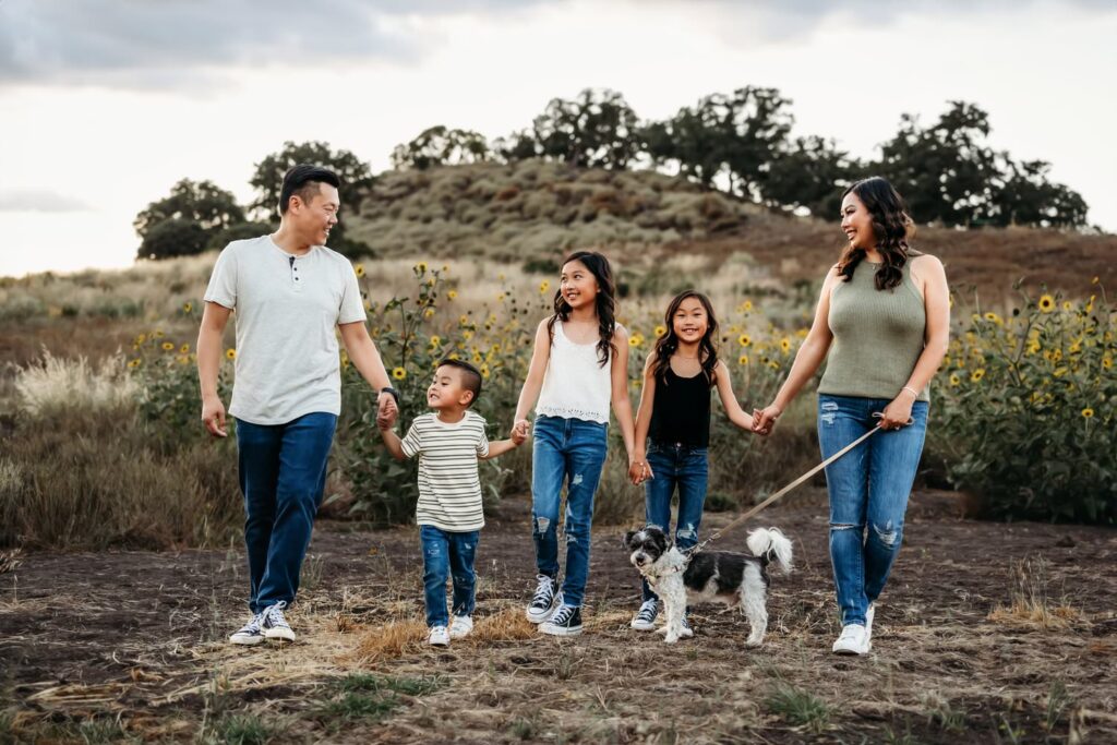 family of 5 walks with their dog at the base of mt diablo with sunflowers behind them
