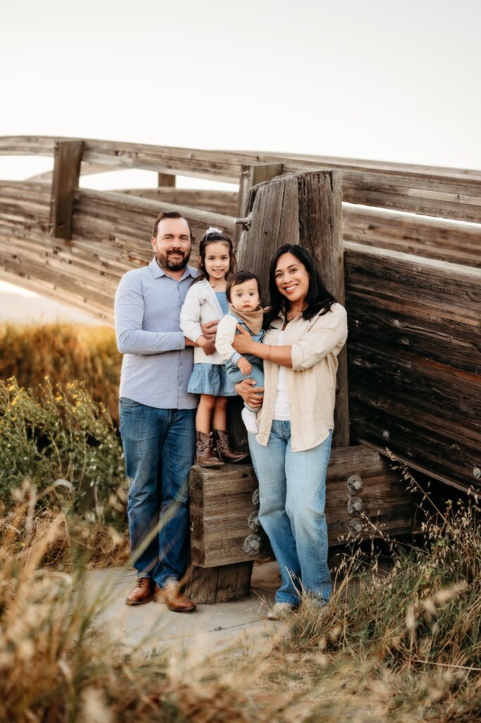 family of 4 posing in front of the martienz bridge all smile and looking at camera
