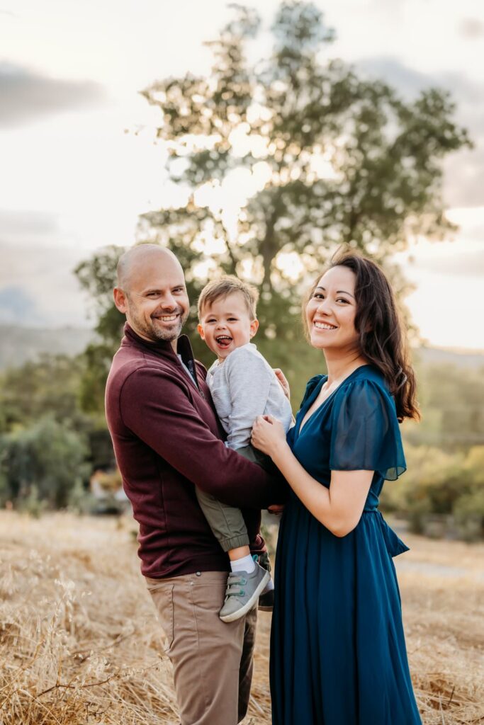parents hold their toddler boy as everyone looks towards the camera