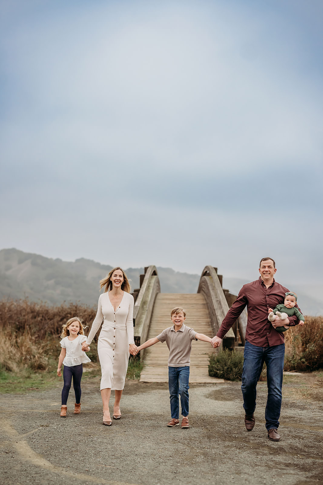 family walking hand in hard away bron the martinez bridge with the briones mts behind them