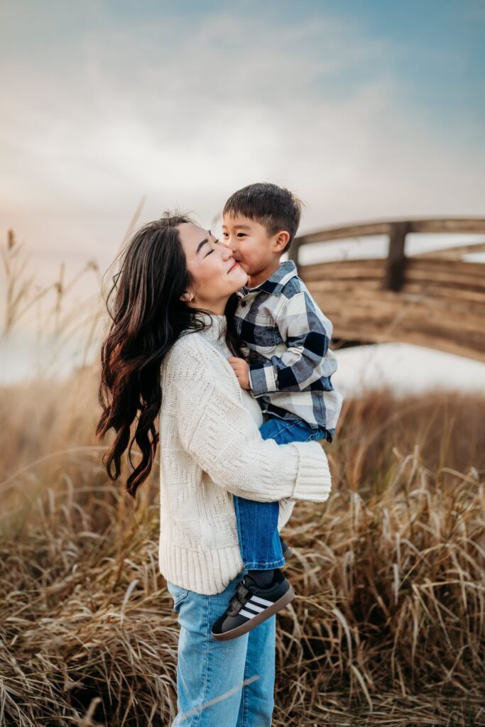silly toddler boy kissing his mom in front of the martinez bridge
