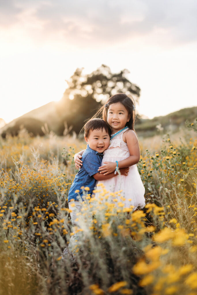 2 kids in a field of yellow and white wildflowers