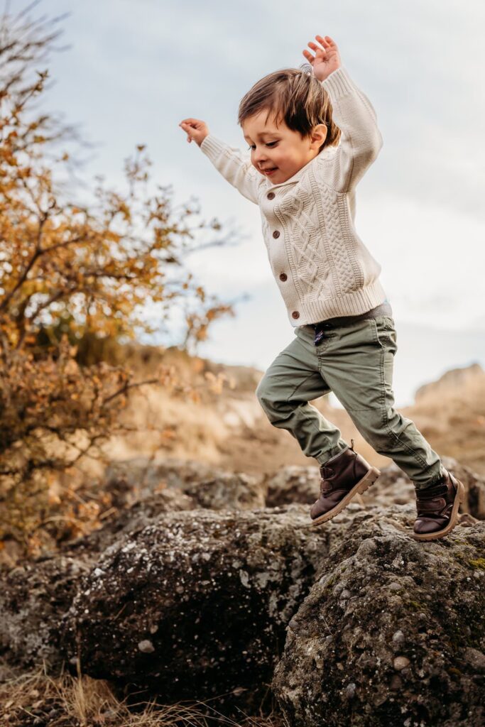 toddler jumping off of a rock during his photo shoot