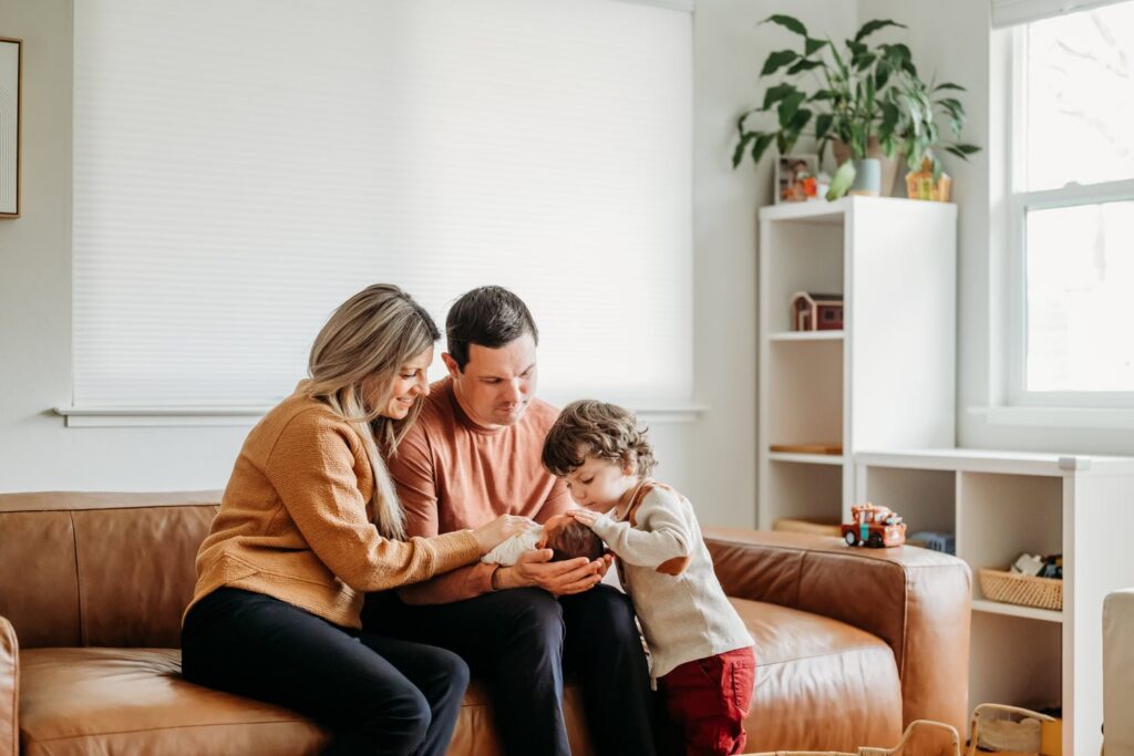A family of three cuddles together on a couch during an in-home newborn photography session in the East Bay